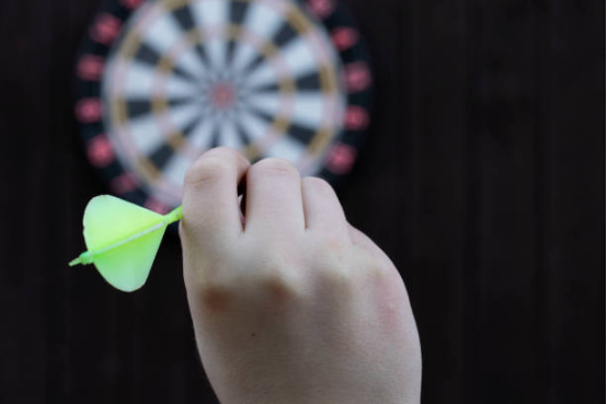 Close-up of a dart player using ambidextrous training to improve dart board accuracy