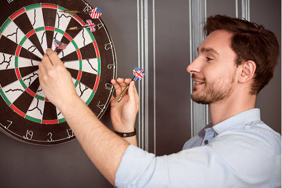 Player throwing darts with Dart board target in the background