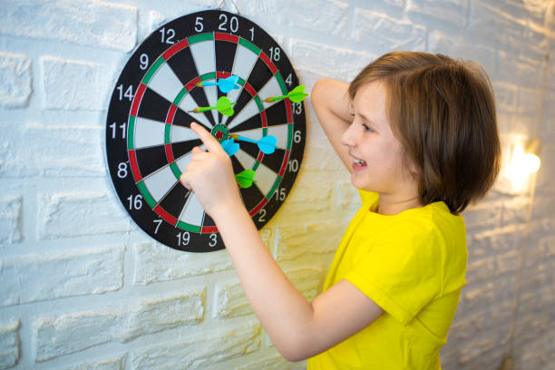 Happy child playing with a magnetic dart board indoors, aiming for the bullseye.