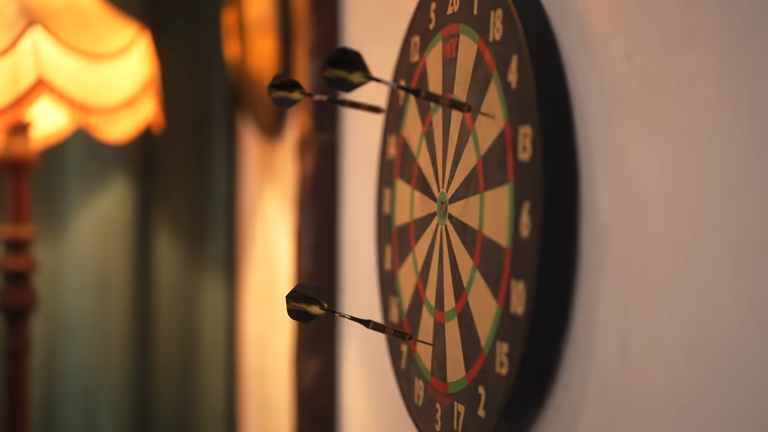 Close-up of a dart board mounted on a wall with several darts hit.