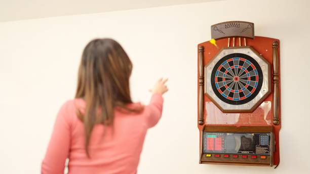 Woman aiming to throw a dart at a vintage electronic dart board.