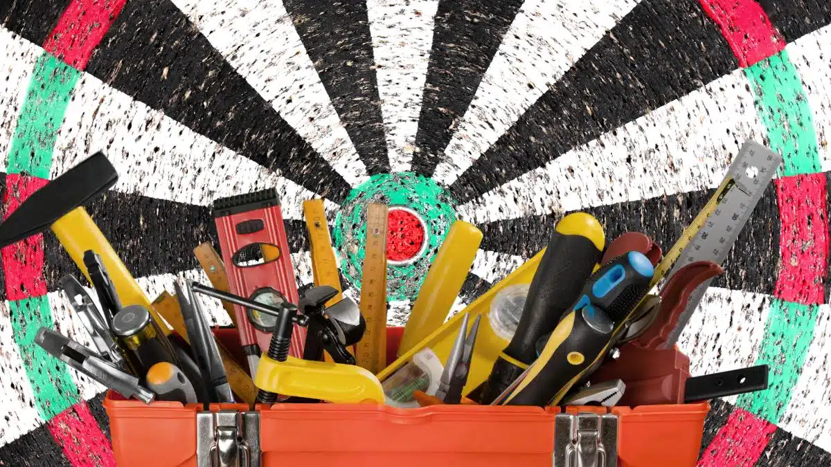 Toolbox overflowing with tools in front of a grunge textured dart board background.