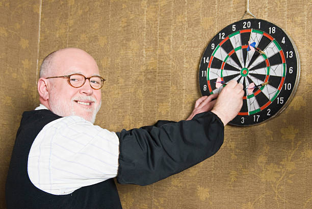 Smiling man collecting darts from a dart board, looking happy.