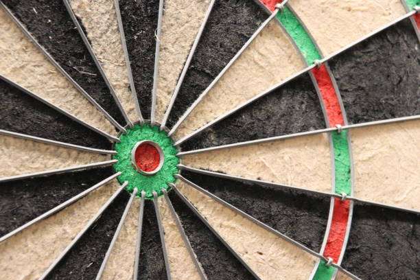 Close-up of a weathered bristle dart board with green bullseye and metal wires.