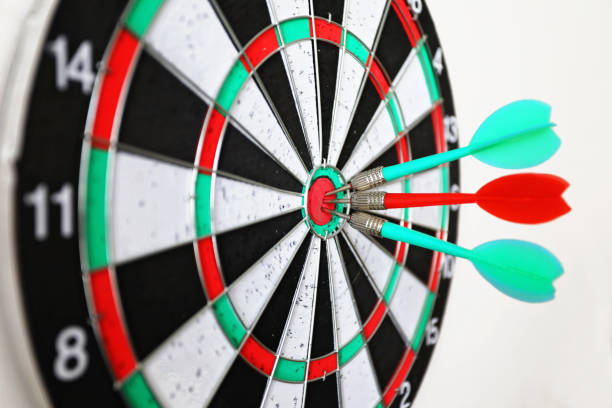 Three darts hit the bullseye of a colorful dart board, showing precision.